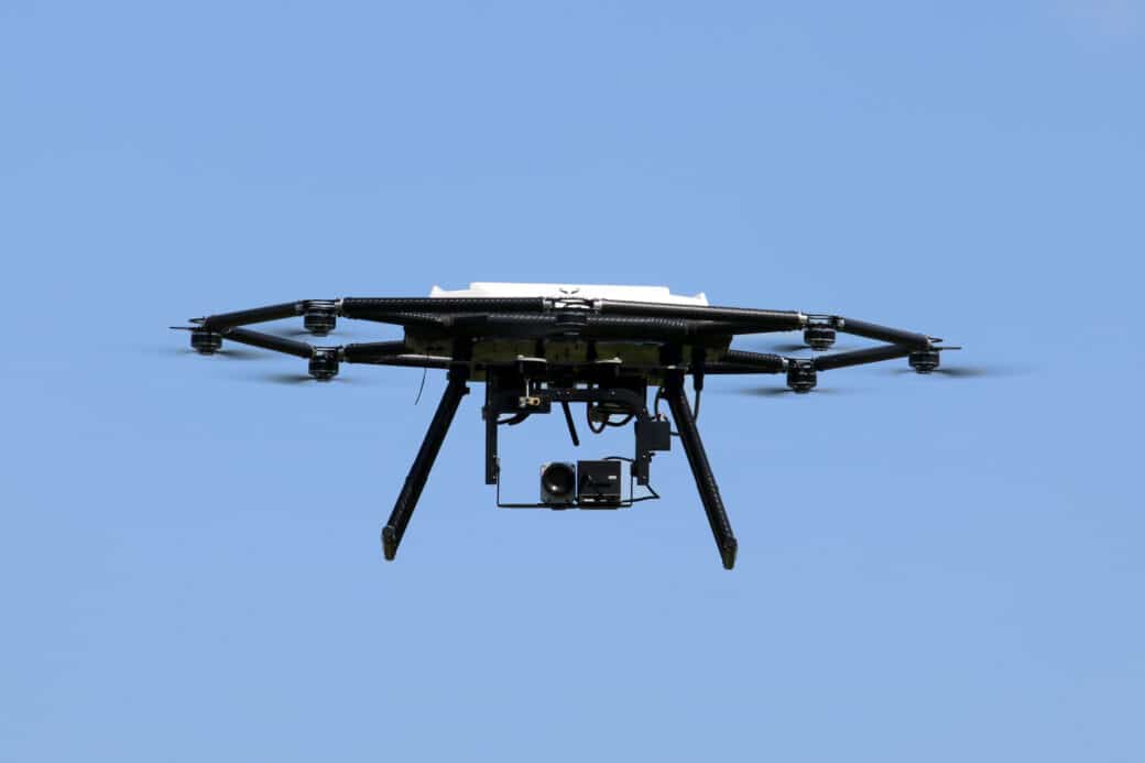 Abbildung: Das Foto zeigt eine vor blauem Himmel schwebende Drohne.