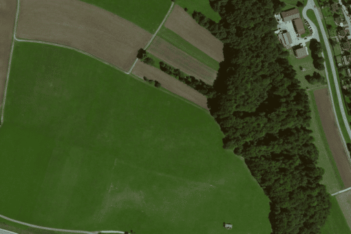 Picture: The aerial photograph shows green overgrown and harvested brown fields next to a piece of forest and a settlement.